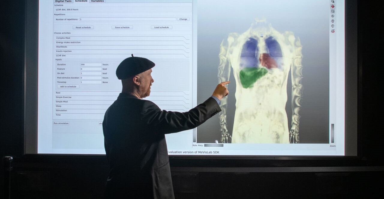 Gunnar Cedersund in front of image illustrating the model of different organs.