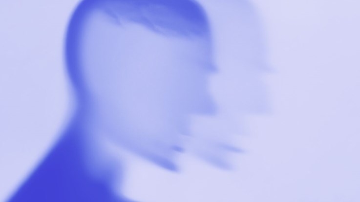 Blurry illustration, silhouette of a head in blue monochrome tones.